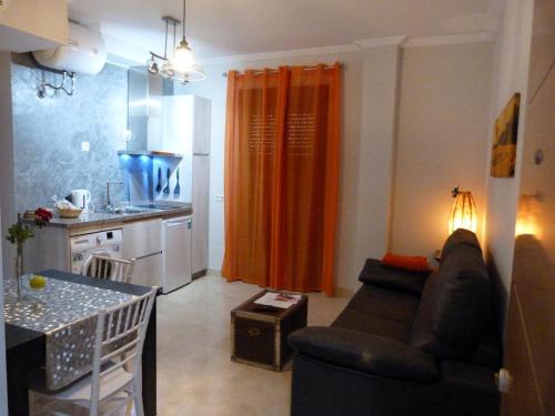安特克拉Najera Suite的带沙发的客厅和带橙色窗帘的厨房