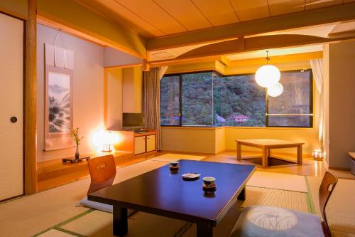 下关Ichinomata Onsen Kanko Hotel的客厅设有桌子和大窗户