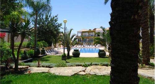 塔维拉Garden Apartment Quinta do Morgado的一座带游泳池和棕榈树的房子