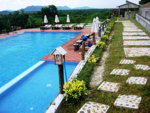 Pailin记忆宫度假酒店的毗邻度假酒店的带椅子和遮阳伞的游泳池
