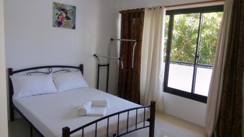 马尼拉The Palines Apartment and Guesthouse - Vista Alabang的一间卧室配有一张带白色床单的床和一扇窗户。