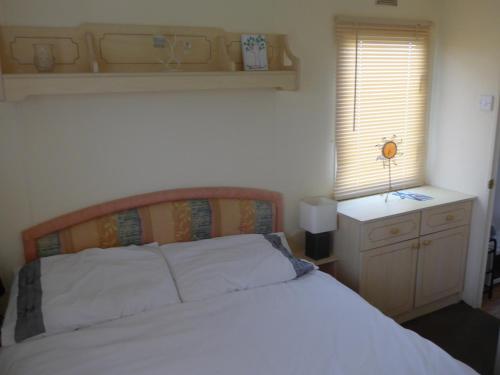 梅布尔索普Mablethorpe L12 Caravan的卧室配有白色的床和窗户。