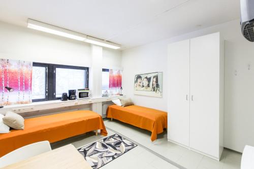 万塔万塔机场奥卢弗雷蒙旅舍的白色客房的两张床,配有橙色床单
