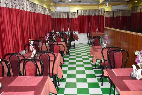 加尔各答Hotel Airways的一间配备有桌椅和红色窗帘的用餐室