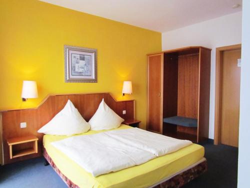 萨尔堡希布里克酒店 的一间卧室设有一张床和黄色的墙壁