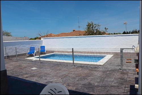 科尼尔-德拉弗龙特拉Casa Rural Zara III的一个带两把蓝色椅子的游泳池,围栏旁