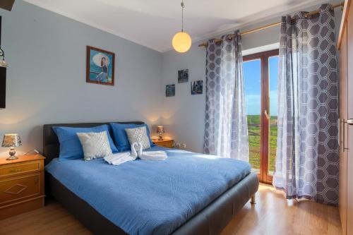 ŠikićiHouse Silvija Pula的一间卧室设有蓝色的床和大窗户