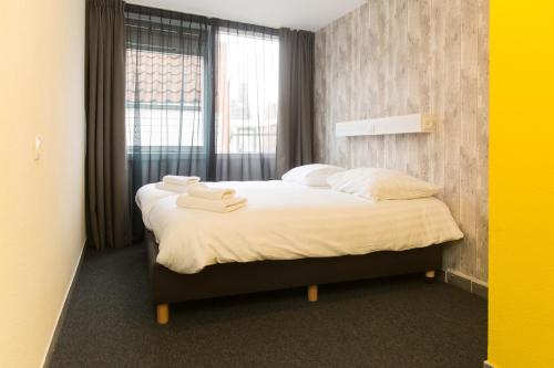 滨海卡特韦克Beach Hotel Katwijk的一间卧室配有一张床,上面有两条毛巾