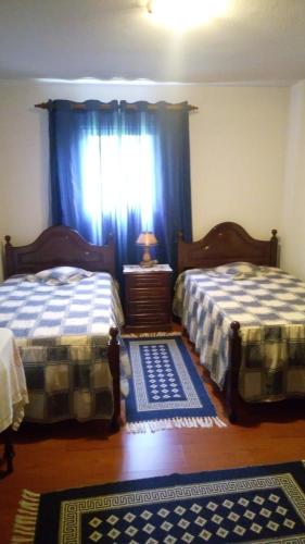 桑塔纳Casa Reis的一间卧室设有两张床,窗户配有蓝色窗帘