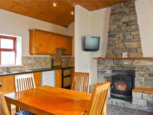 巴林罗布Cavan Hill Cottage的厨房配有木桌和石制壁炉。