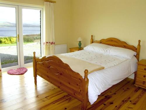 瓦特维尔Lough Currane Cottage的一间卧室设有一张木床和一个大窗户。