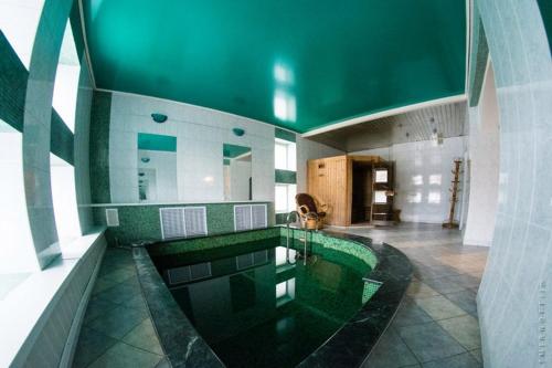 雷宾斯克Gostevoy Dom Hotel的一座带绿色天花板的建筑中的游泳池