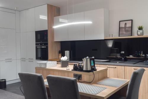 若雷Apart-Hotel VIVI RESIDENCE & SPA的厨房配有白色橱柜和桌椅