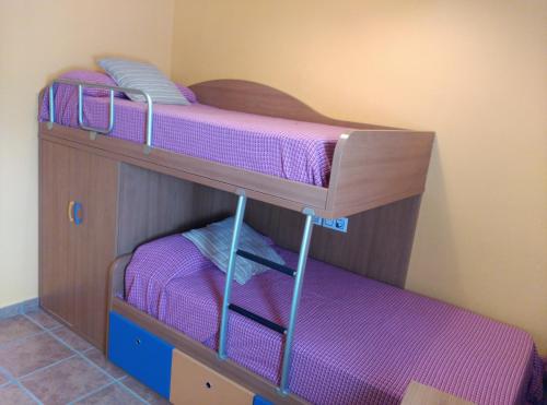拉斯内格拉斯Bonito apartamento的配有紫色床单的客房内的两张双层床