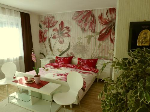 阿诺尔德施泰因Ferienhaus Kramser的一间卧室配有一张带红色枕头的床和花卉壁纸