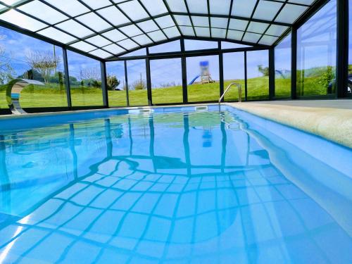 塔皮亚德卡萨列戈Hotel La Casa Del Abuelo的一个带玻璃天花板和蓝色海水的室内游泳池