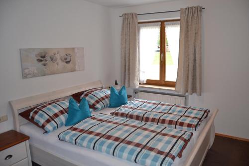 瓦尔兴湖Almwohnung Neuner的一间卧室配有一张带蓝色枕头的床和一扇窗户。