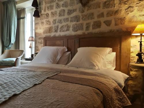 BrévandsChateau Le Colombier的一间卧室设有一张带石墙的大床