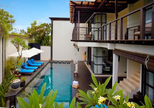 金巴兰寺山别墅酒店的一座带蓝色躺椅的室外游泳池,位于大楼旁