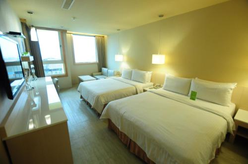 高雄康桥商旅 - 光荣码头的酒店客房,设有两张床和一张沙发