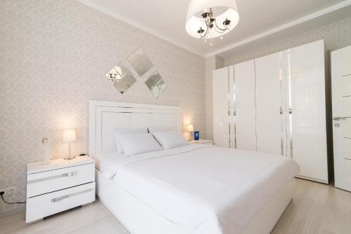 布雷斯特普希金城市生活公寓的白色卧室配有一张白色大床和吊灯