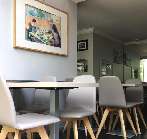 图尔米拉波酒店的一间带桌子和白色椅子的用餐室