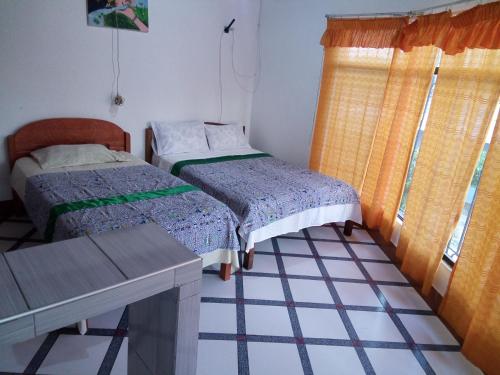 伊基托斯Sarisa House的客房设有两张床、一张桌子和一扇窗户。