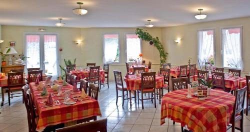 Saint-Martin-sous-VigourouxHotel De La Poste的餐厅配有桌椅和红色桌布
