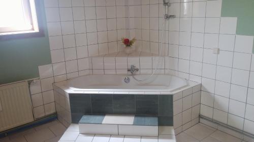 菲拉赫城市奉献公寓的白色瓷砖浴室设有浴缸和花瓶