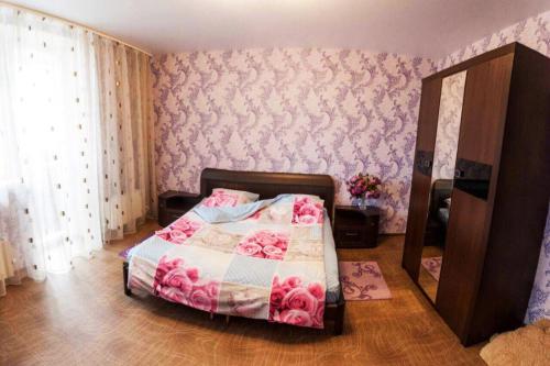 秋明Apartment on Gazovikov 41的一间卧室配有一张粉红色花卉壁纸的床