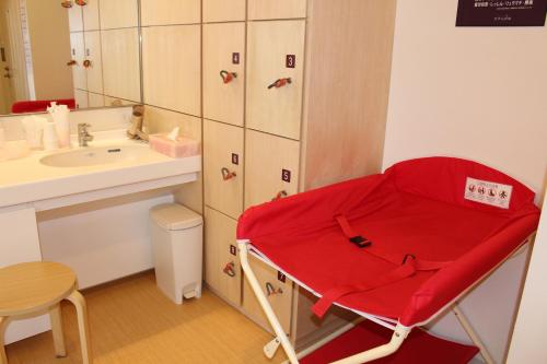 苫小牧市苫小牧杉田酒店的一个带水槽的浴室内的红色椅子