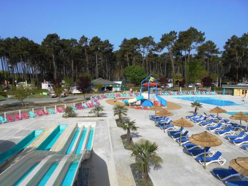 波讷地区圣朱利安Camping Officiel Siblu Les Dunes de Contis的度假村的游泳池设有椅子和水滑梯