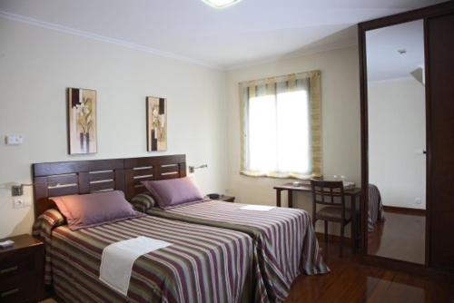 诺盖拉德拉姆达雷萨赌场酒店的一间卧室配有一张带条纹毯子的大床