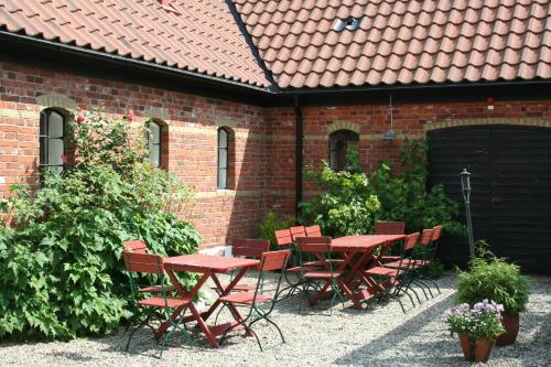 奇维克布拉辛伯格斯嘉德舒特尔旅馆的砖砌建筑前的庭院,配有红色的桌椅