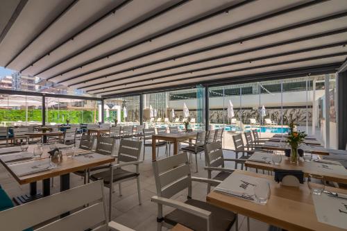 马马亚Nyota Hotel & Conference Center的一间带桌椅的餐厅和一个游泳池