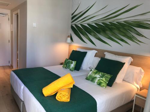 帕格拉BQ Paguera Boutique Hotel - Adults Only的一间卧室配有一张带绿色和黄色枕头的床