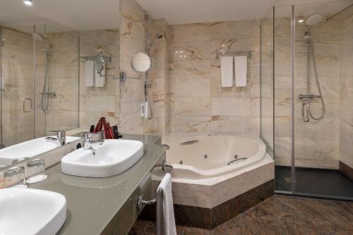 马德里拉斐尔阿托查酒店的浴室配有2个盥洗盆、浴缸和淋浴。