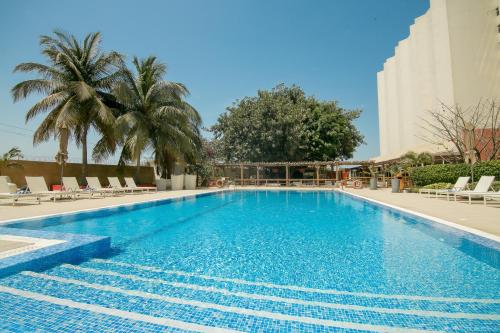 达喀尔诺富特达喀尔酒店的一座带椅子和棕榈树的游泳池以及一座建筑