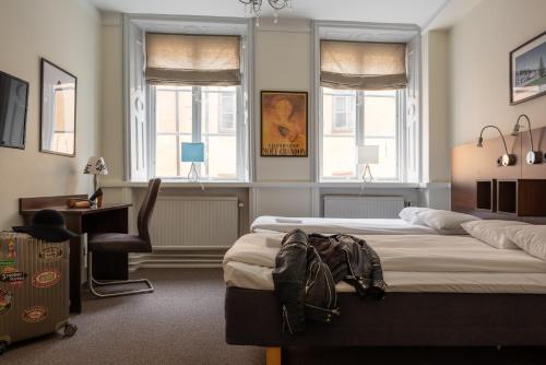 斯德哥尔摩城堡庄园酒店 的一间卧室配有两张床、一张桌子和两个窗户。