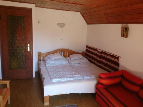 鲍洛通塞迈什Balatonszemes Nyaraló的一间卧室配有一张床和一张红色的沙发