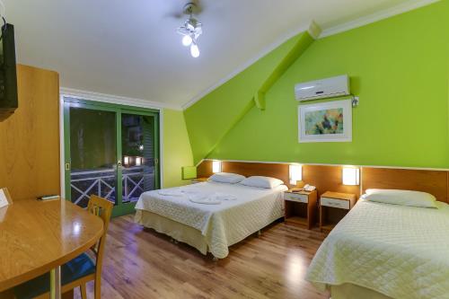 新彼得罗波利斯Vila Rica Pousada的一间卧室设有两张床和绿色的墙壁