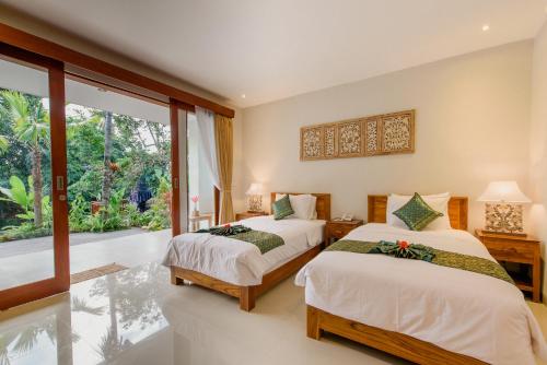 乌布Taman Amartha Hotel的一间卧室设有两张床和大窗户