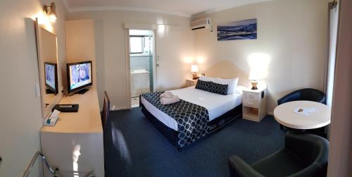库纳巴拉布兰琥珀阁汽车旅馆的酒店客房配有一张床、一张书桌和一台电视。