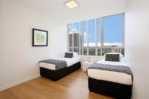 悉尼G1708S三卧室泽特蓝公寓的带大窗户的客房内的两张床