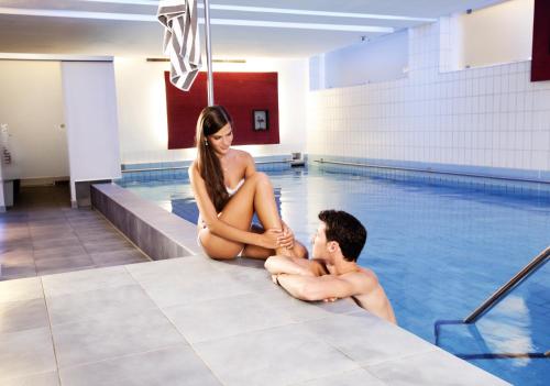 腓特烈港科隆市酒店的坐在游泳池里的男人和女人