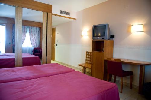 La Alameda de la SagraHotel La Maruxiña的酒店客房设有两张床、一张桌子和一台电视。