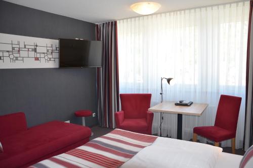 科赫姆Flair Hotel am Rosenhügel - Garni的酒店客房,配有一张床和两张红色椅子