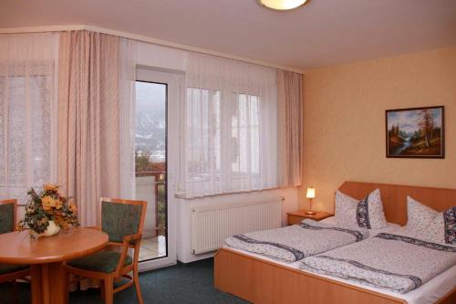 巴特尚道Hotel-Garni Elbgarten Bad Schandau的一间卧室配有一张床、一张桌子和一个窗户。