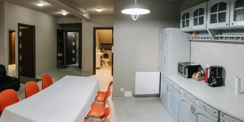 克卢日-纳波卡Meteor apartment XXL的厨房配有白色的桌子和橙色的椅子