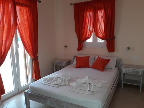 安迪帕罗斯岛叶莱妮酒店的一间卧室配有红色窗帘和一张带红色枕头的床